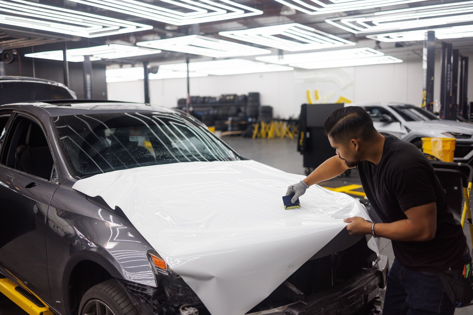 Illustration of an installer applying vinyl wrap to a car hood